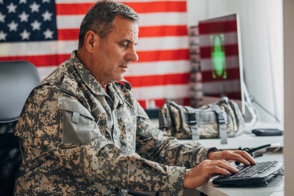  American soldier sitting in headquarters office alone, using computer.