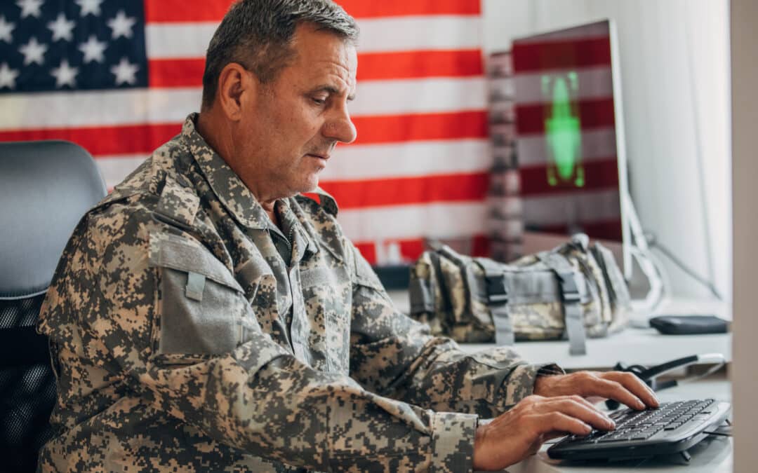 American soldier sitting in headquarters office alone, using computer to write a SITREP.