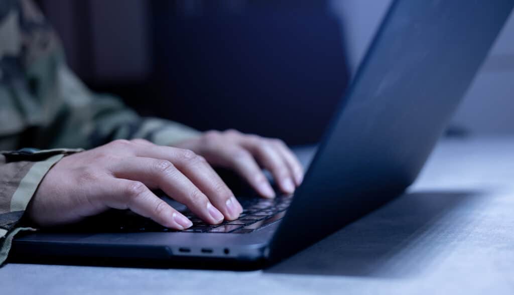 Closeup image of soldier's hands at a laptop keyboard