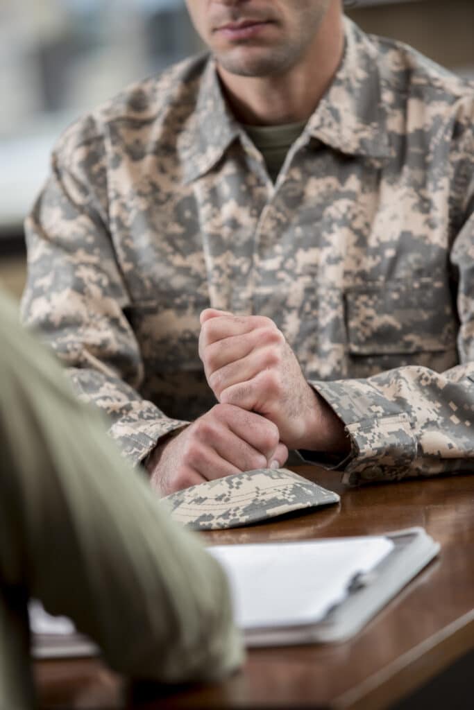 Soldiers in uniform sit on military transport crates, analyze data on a laptop.