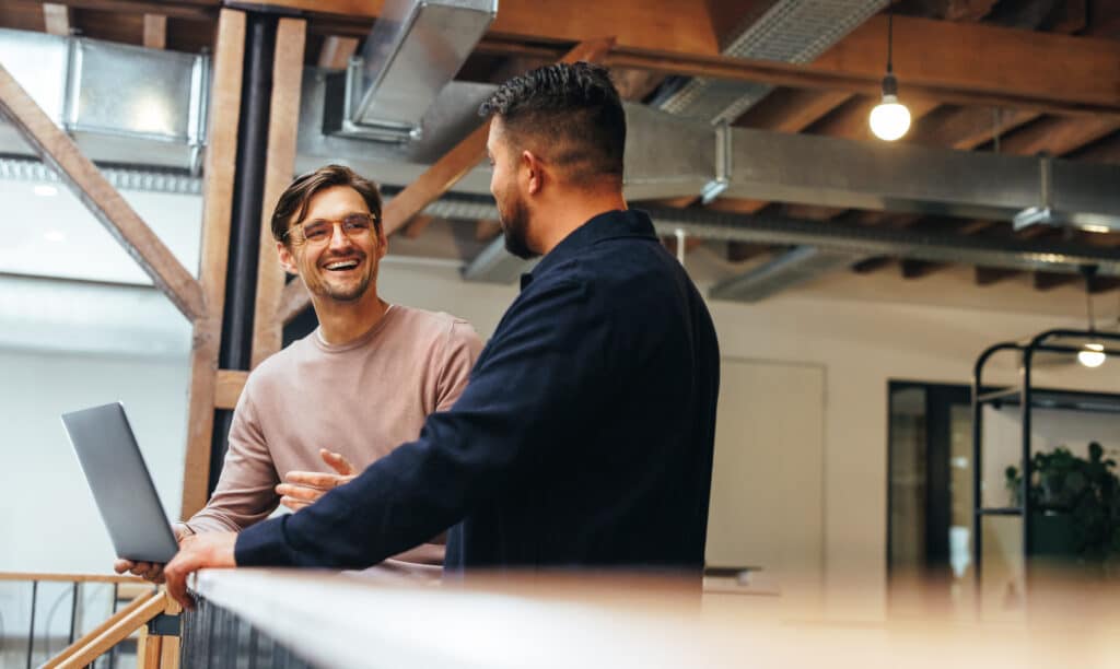Humanity first concept showing two business men talking to each other about their tech work.