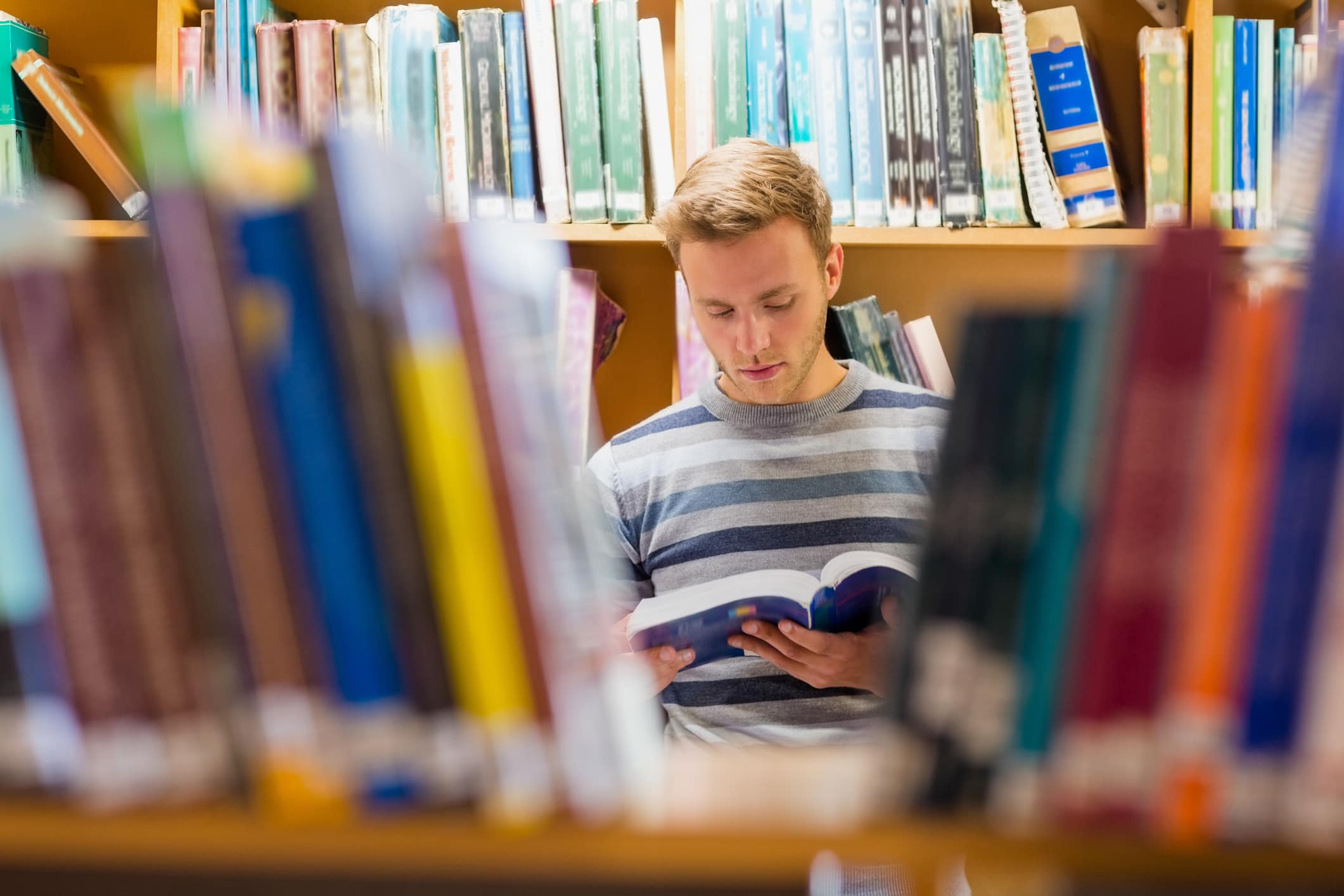 Close reading: Male student reading a book in the library